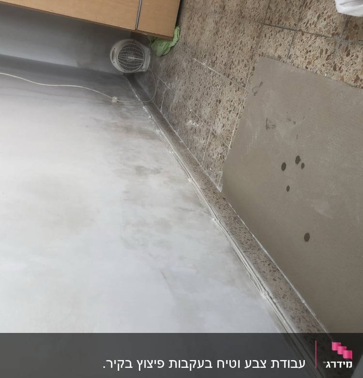 קיר צבוע חלקית עם סימני צבע על הרצפה
